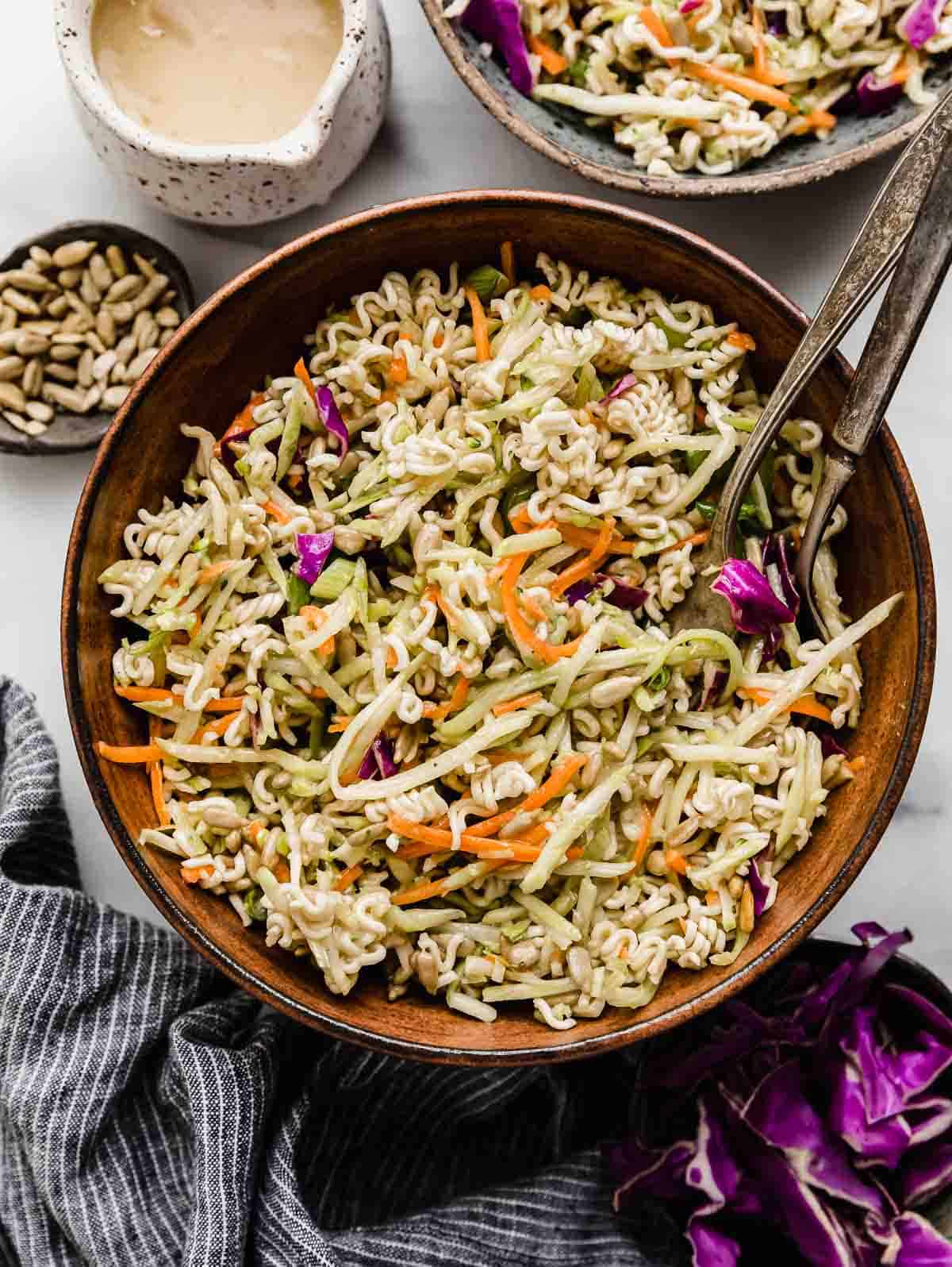 Asian Broccoli Slaw in a brown bowl with ramen and sesame seeds in the salad.