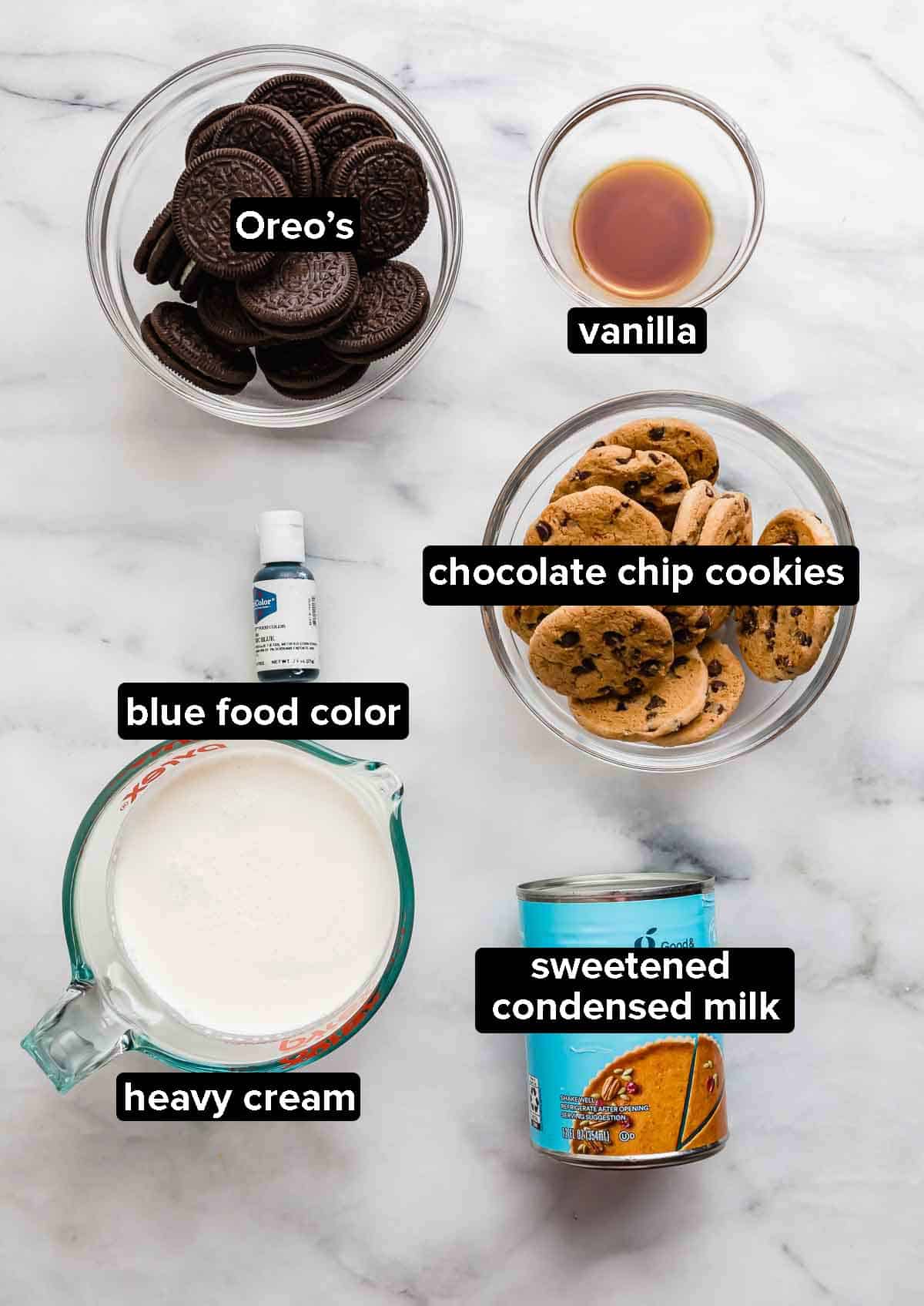 Cookie Monster Ice Cream ingredients on a white marble background: ingredients include Oreos, chocolate chip cookies, vanilla, heavy cream, and sweetened condensed milk.