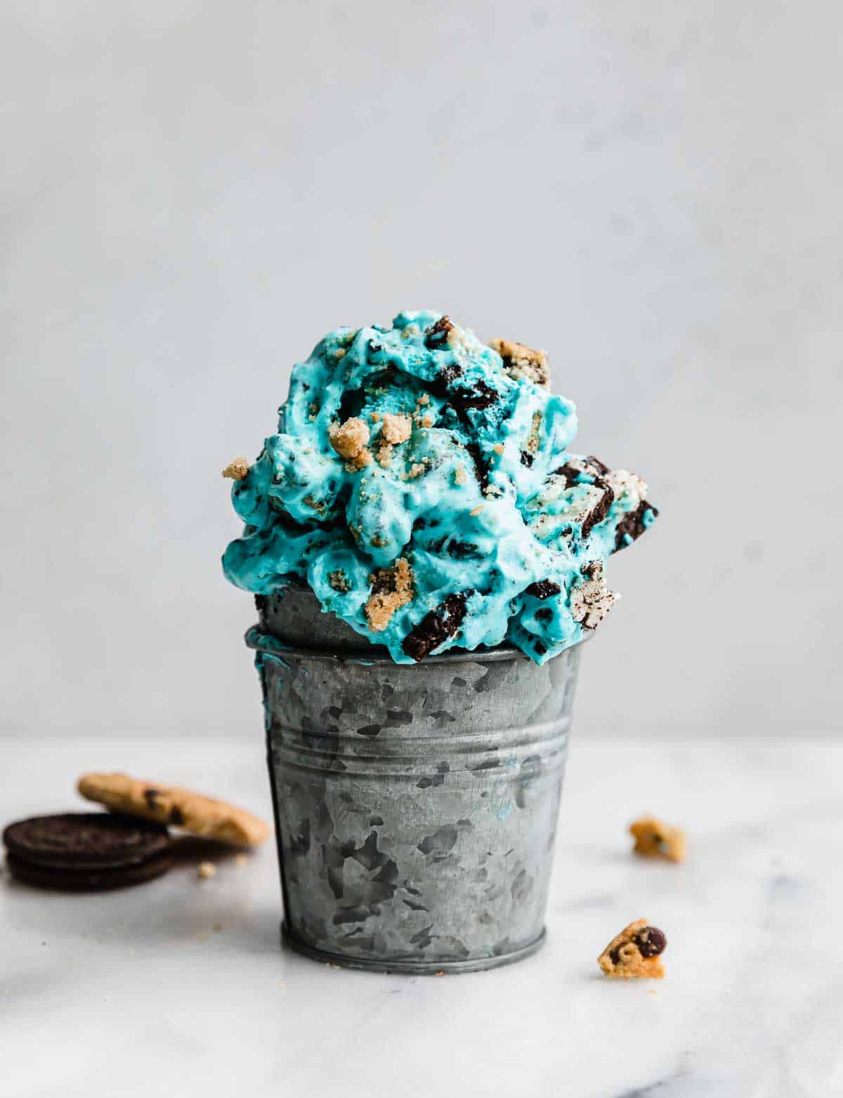 Small metal cup filled with blue Cookie Monster Ice Cream against a white background.