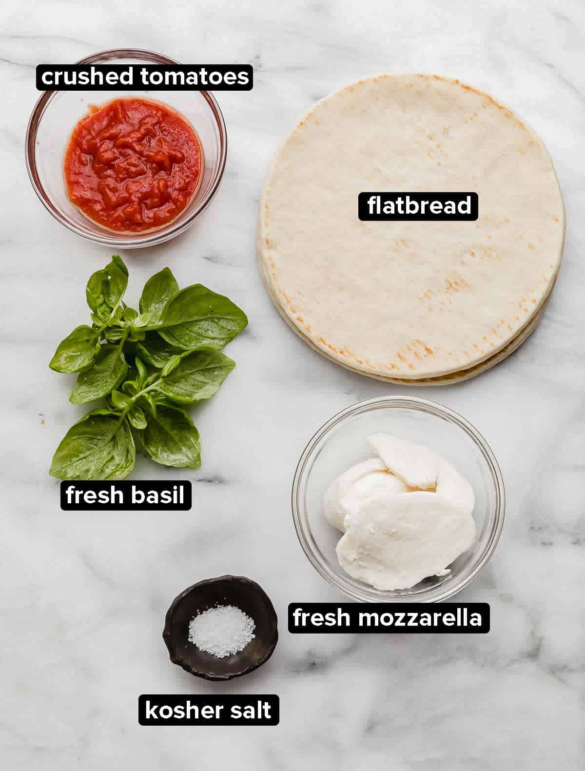 Margherita Flatbread pizza recipe ingredients on a white background: flatbread, crushed tomatoes, fresh basil, kosher salt, and mozzarella.