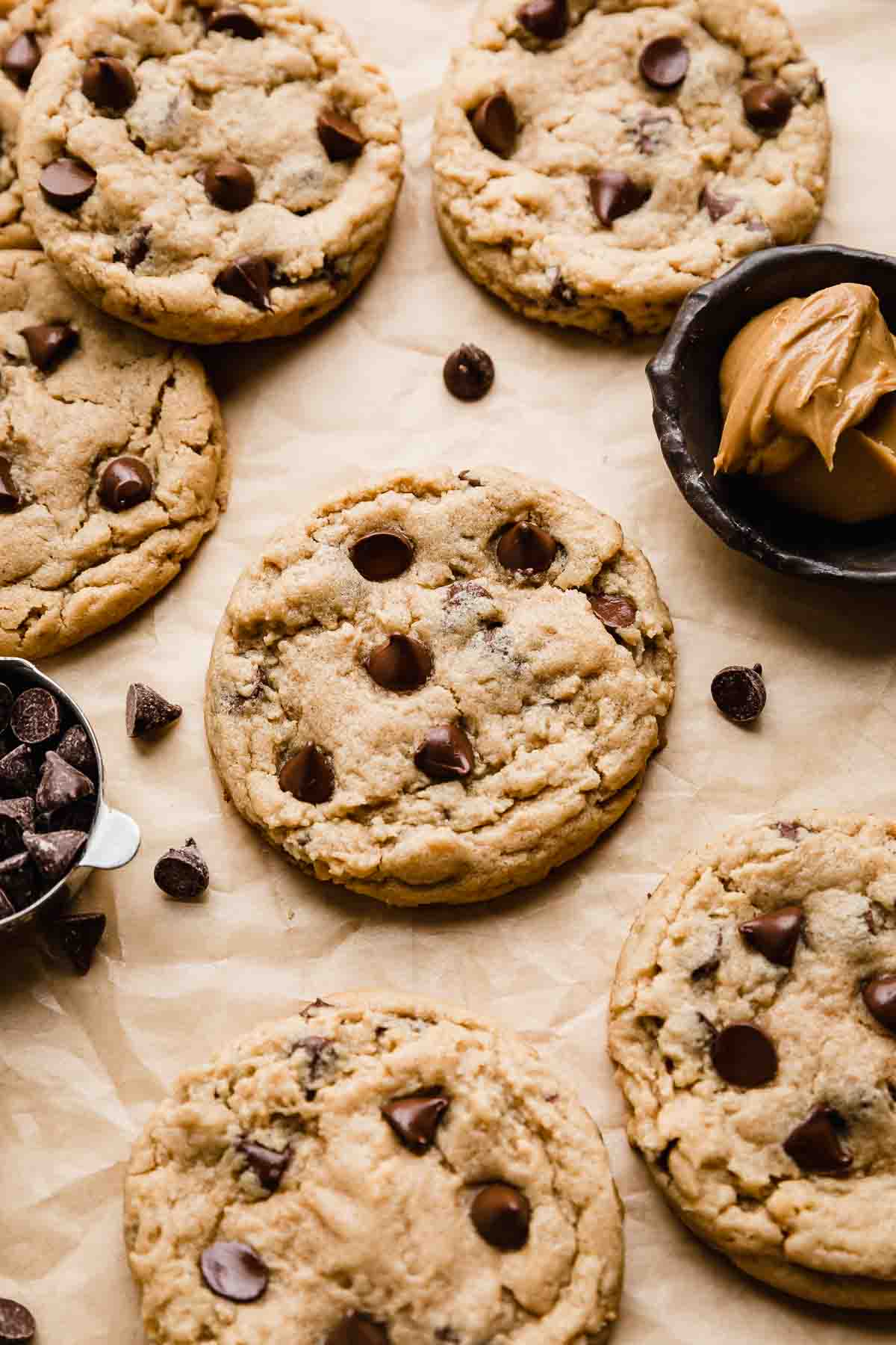 Chocolate chip peanut butter cookies on a light brown background with chocolate chips scattered around the cookies.