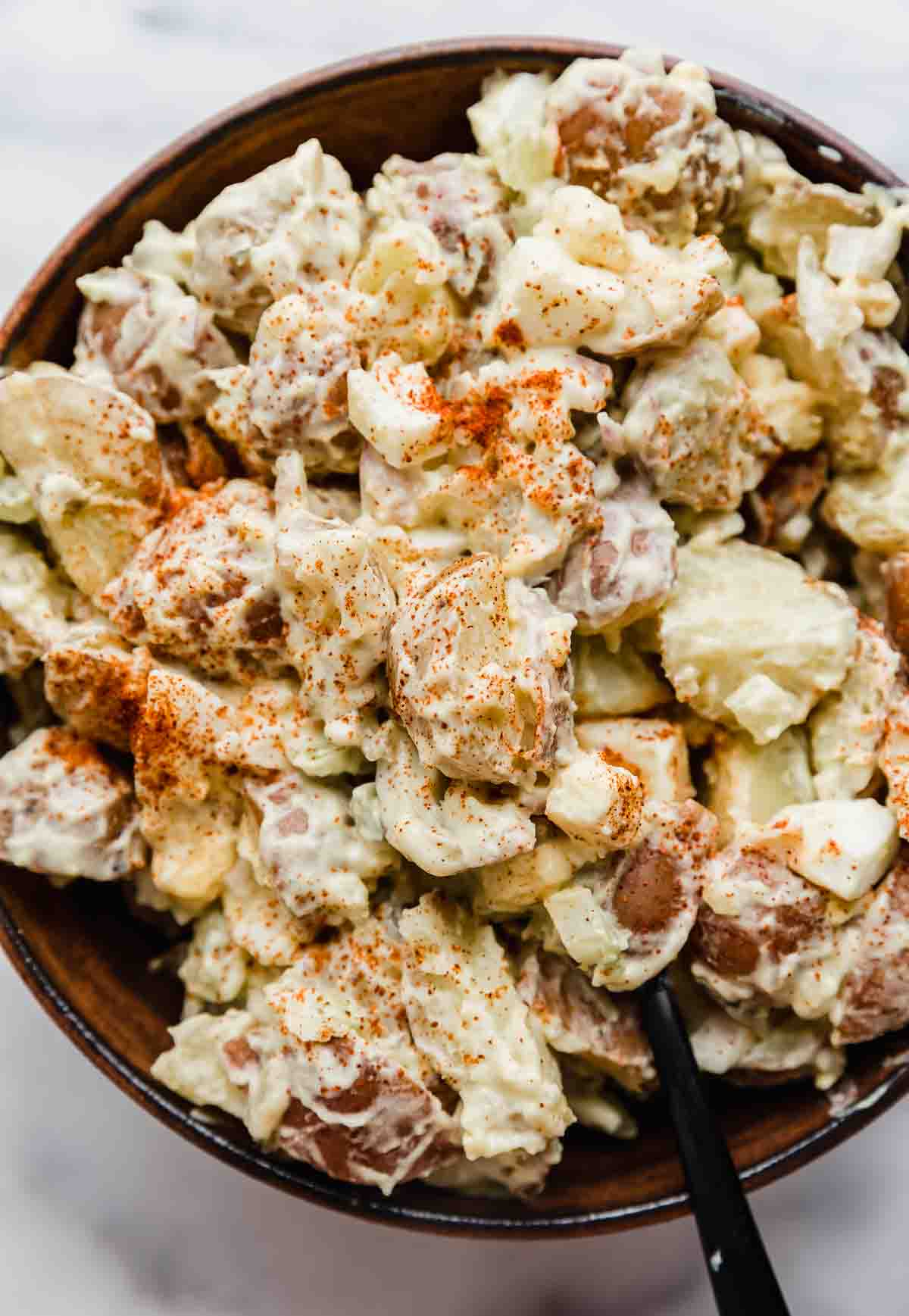 Paprika topped baby potato salad recipe in a bowl on a white background.