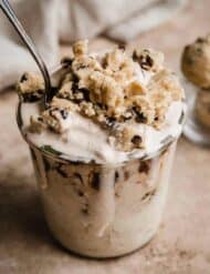 Chocolate Chip Cookie Dough Blizzard in a glass cup on a light brown textured background.