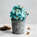Metal cup filled with Cookie Monster Ice Cream loaded with Oreo pieces and chocolate chip cookie chunks.