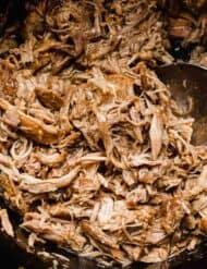 A close up photo of shredded Mississippi Pork Roast in a black crock pot.