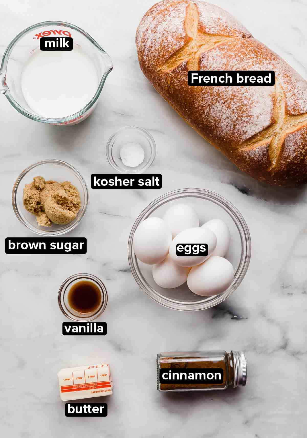 French Bread French Toast ingredients on a white background, ingredients include: French bread, eggs, butter, cinnamon, vanilla, brown sugar, and milk.