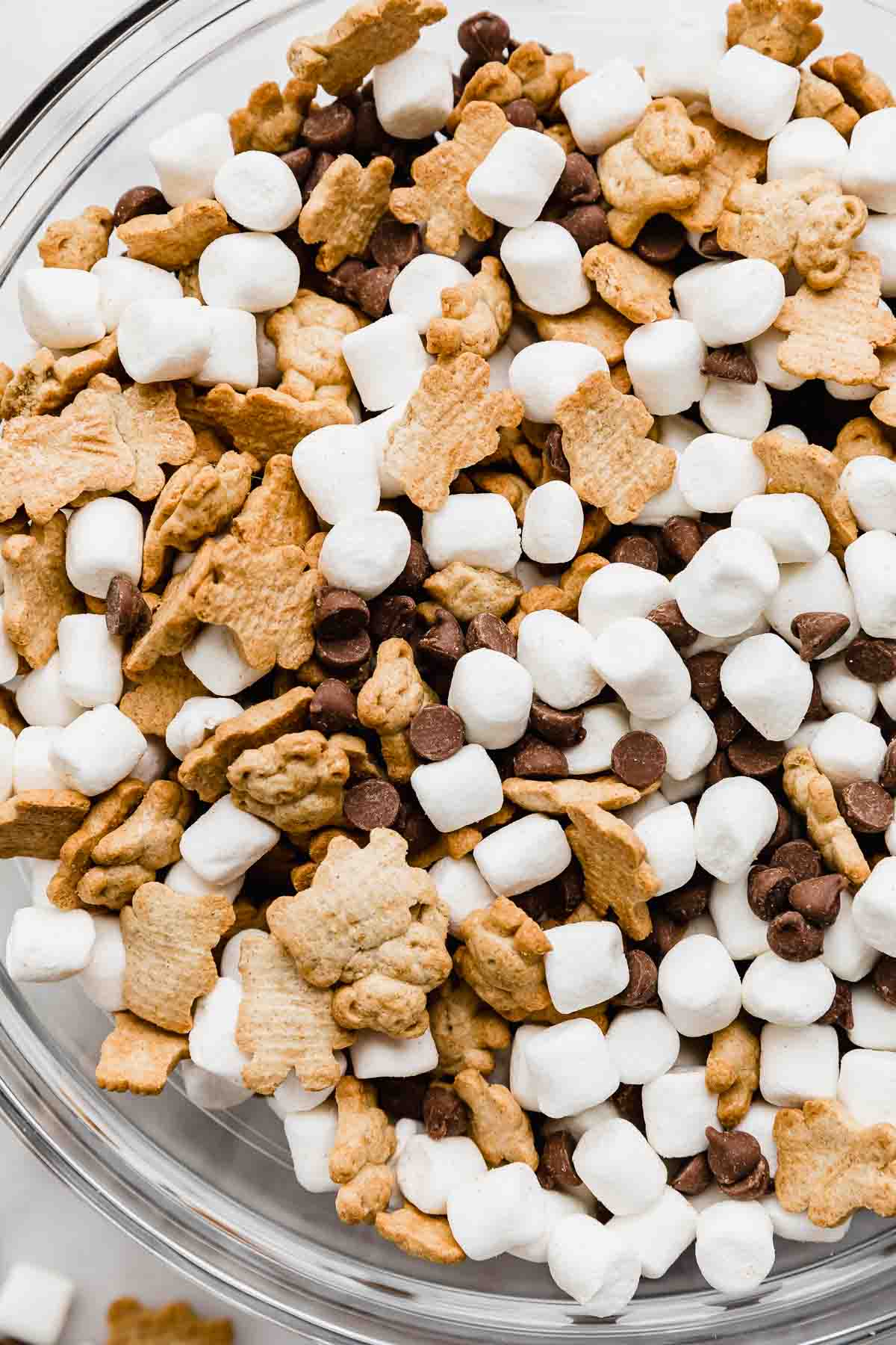 A close up of a S'mores Mix in a glass bowl (milk chocolate chips, marshmallows, and teddy grahams).