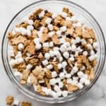 A large glass bowl filled with S'mores Mix: mini marshmallows, chocolate chips, and teddy grahams.