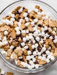A large glass bowl filled with S'mores Mix: mini marshmallows, chocolate chips, and teddy grahams.