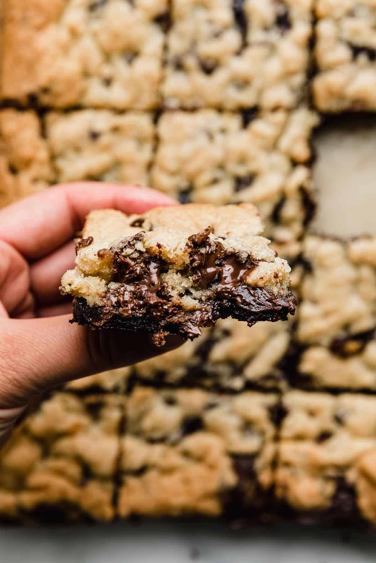 A hand holding a Brookie (chocolate chip brownie bar).