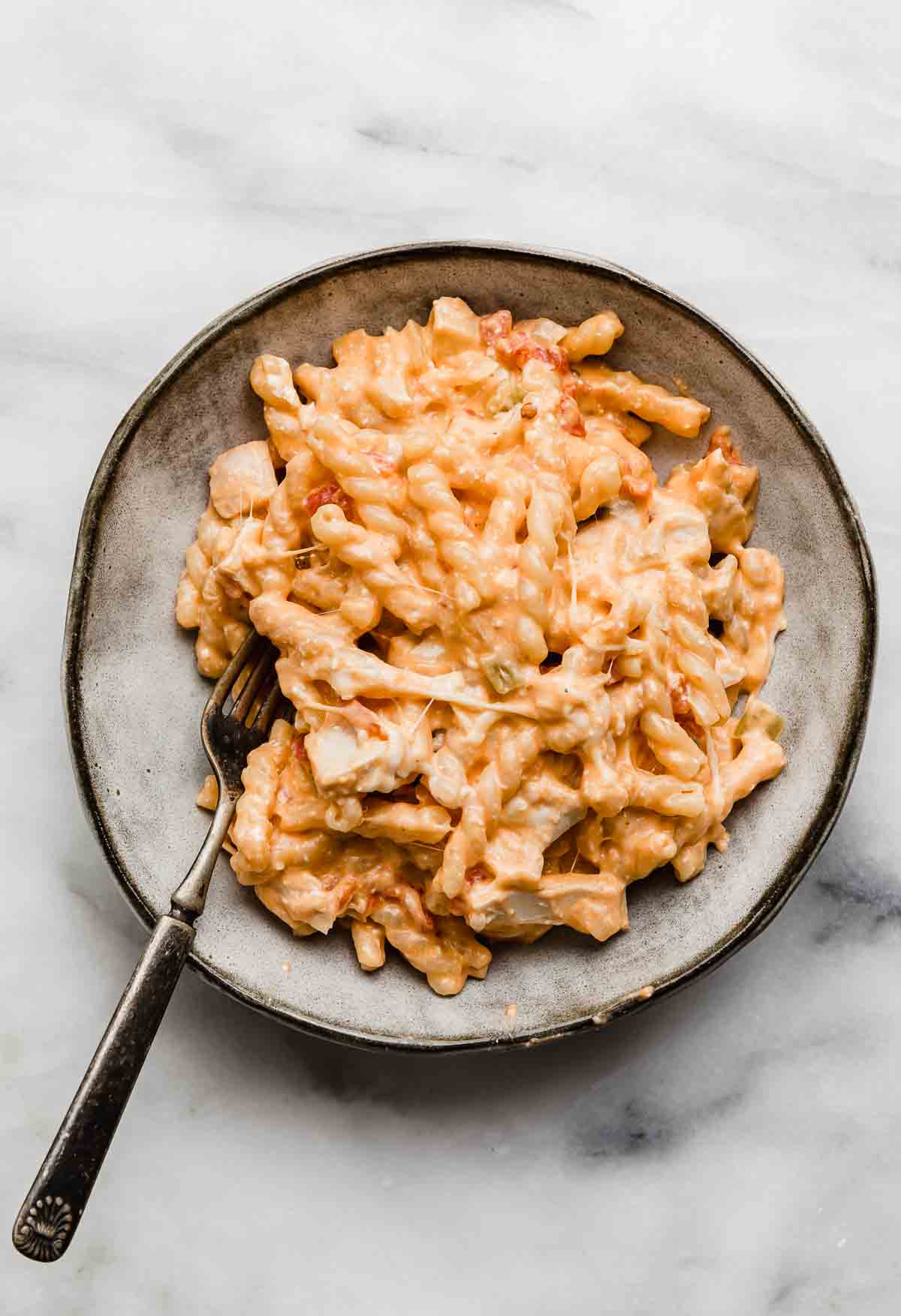 A gray bowl with Buffalo Chicken Pasta, on a white marble background.