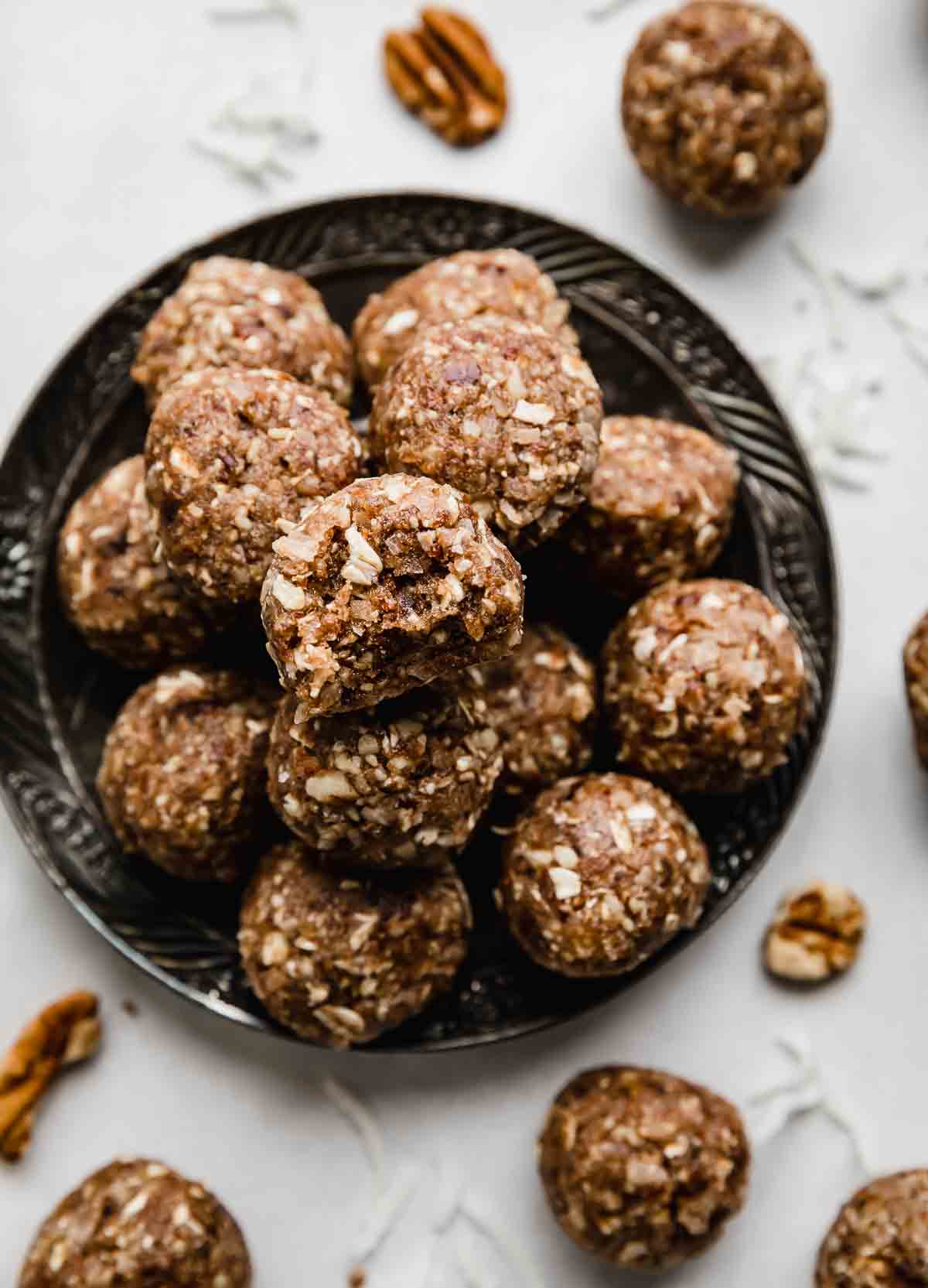 German Chocolate Cake Protein Balls stacked on a black plate on a white background.