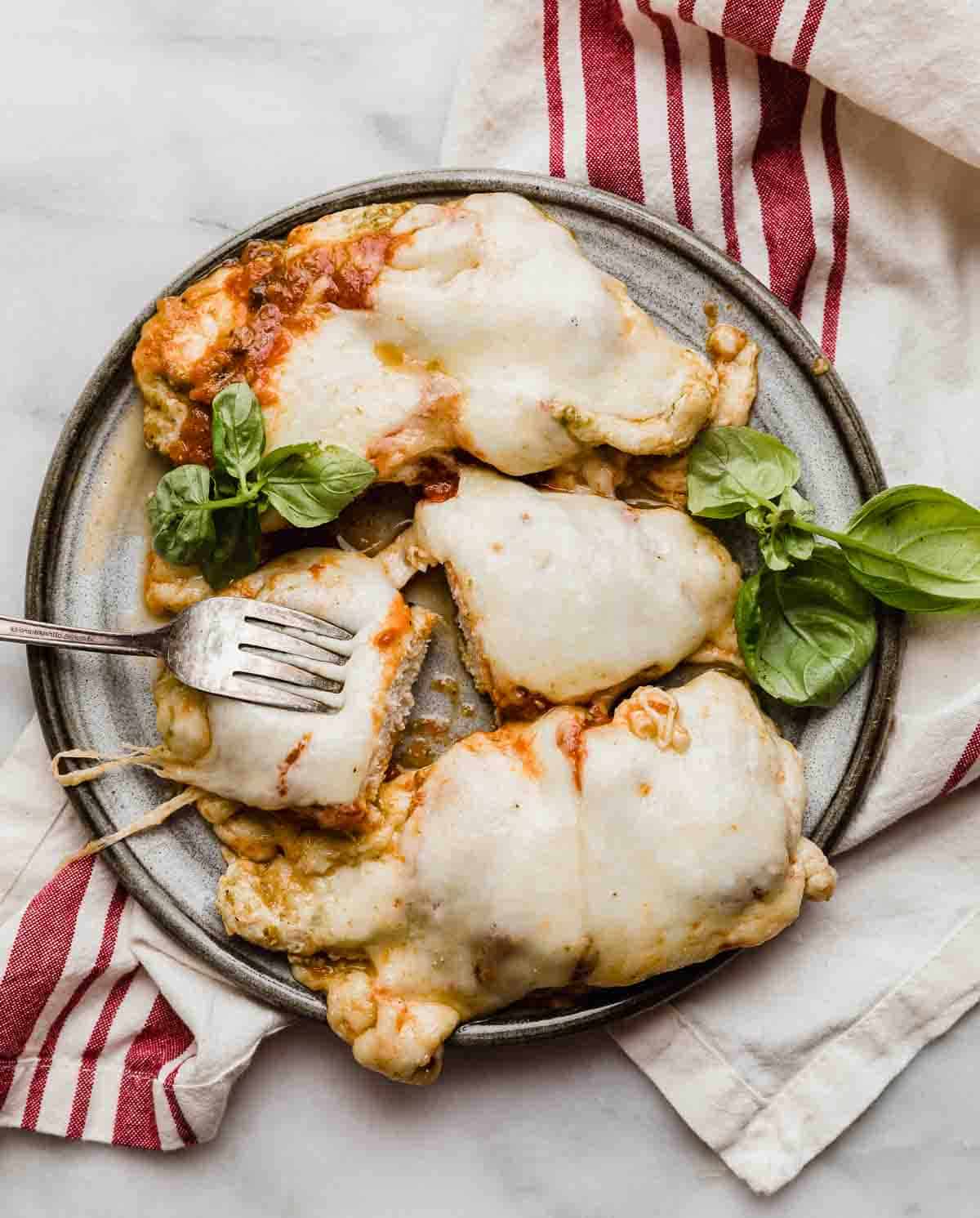 A gray plate topped with 3 pieces of Pesto Chicken Parmesan.