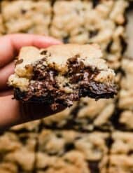A hand holding a Brookie (chocolate chip brownie bar).