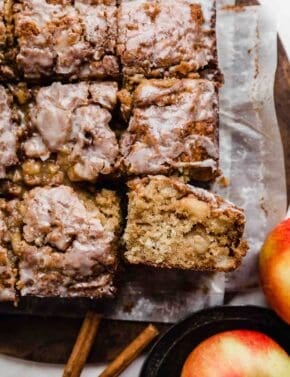 An Apple Fritter Cake sliced into squares on parchment paper.