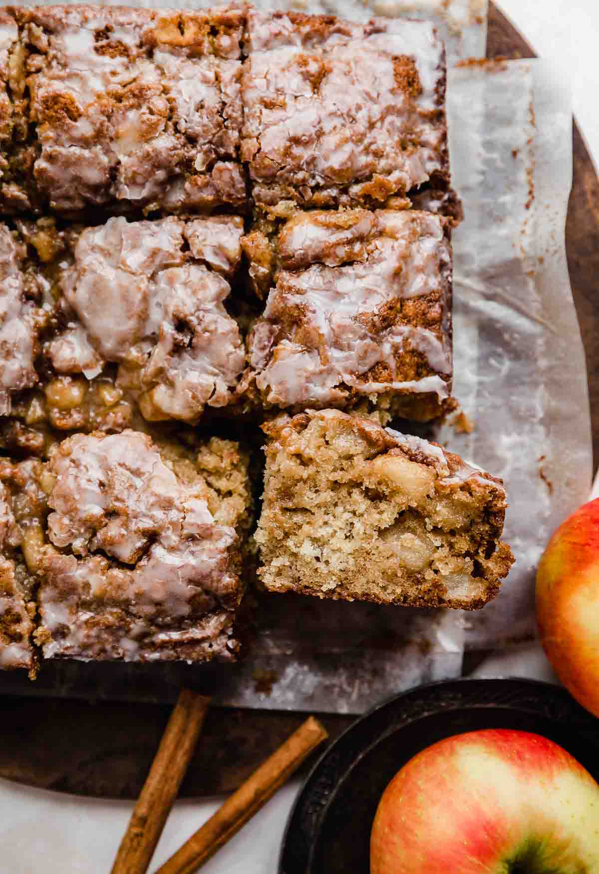 An Apple Fritter Cake sliced into squares on parchment paper.