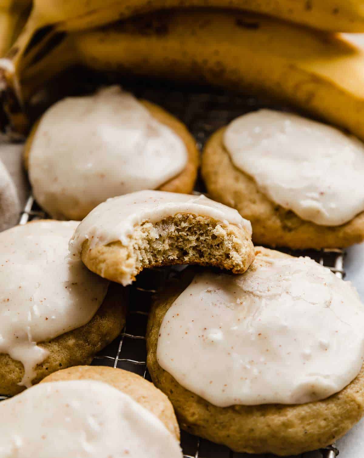 A bite taken out of a banana cookie frosted with brown butter frosting.