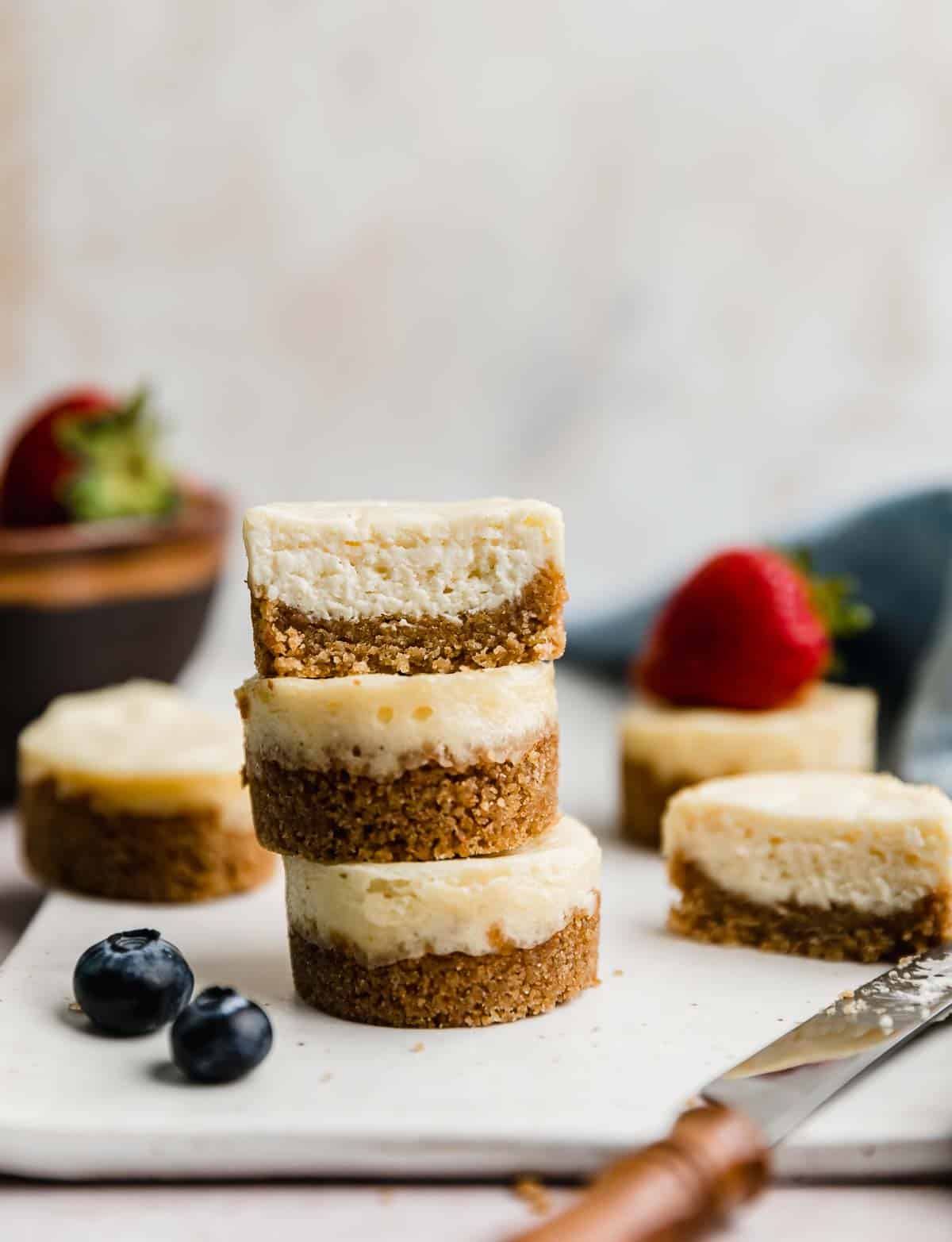 Three Mini Cheesecakes stacked on top of each other against a light cream background.