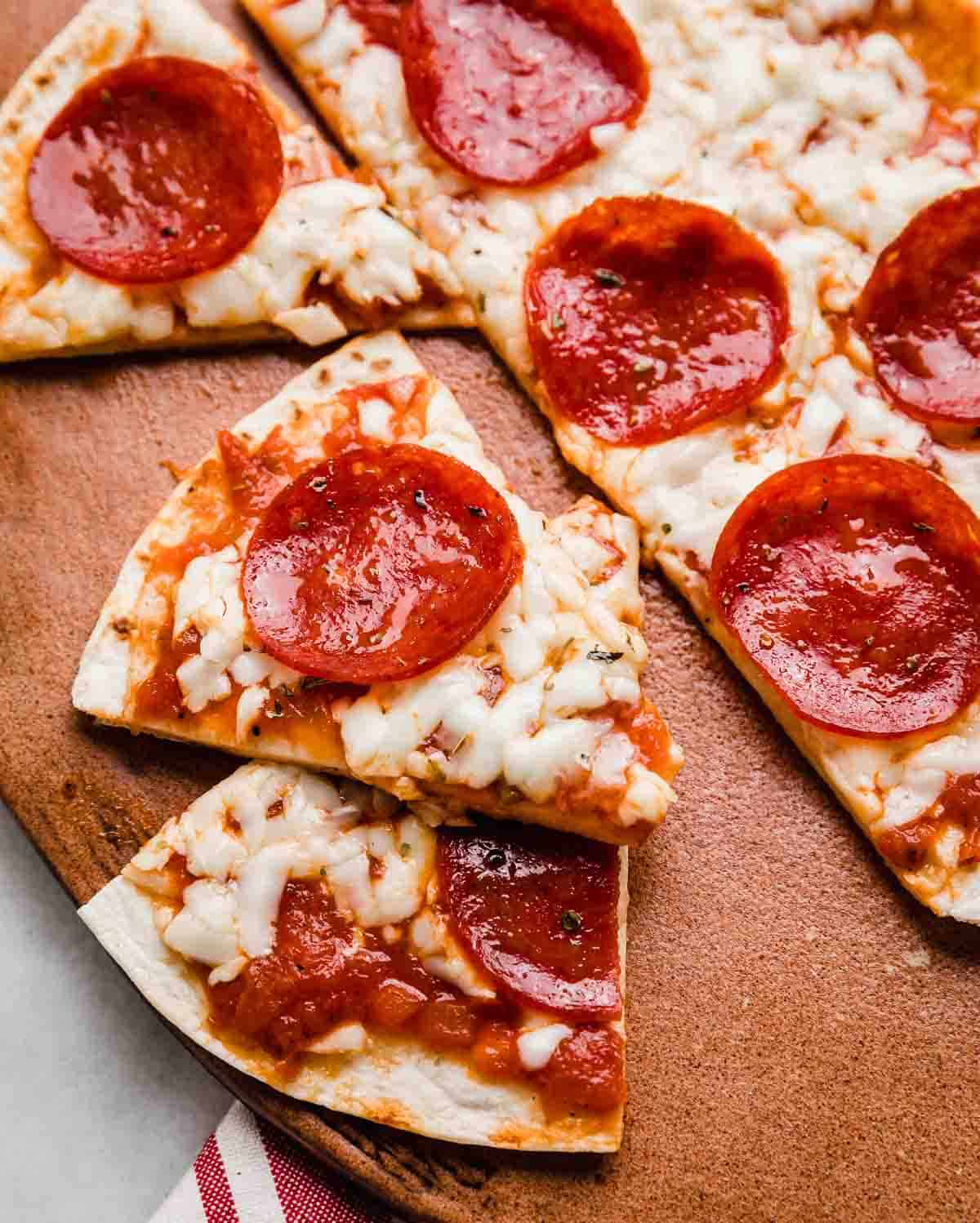 Tortilla Pizza cut into triangles on a brown plate.