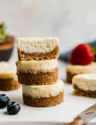 A mini cheesecake cut in half, and stacked on two additional small cheesecakes on a white plate.