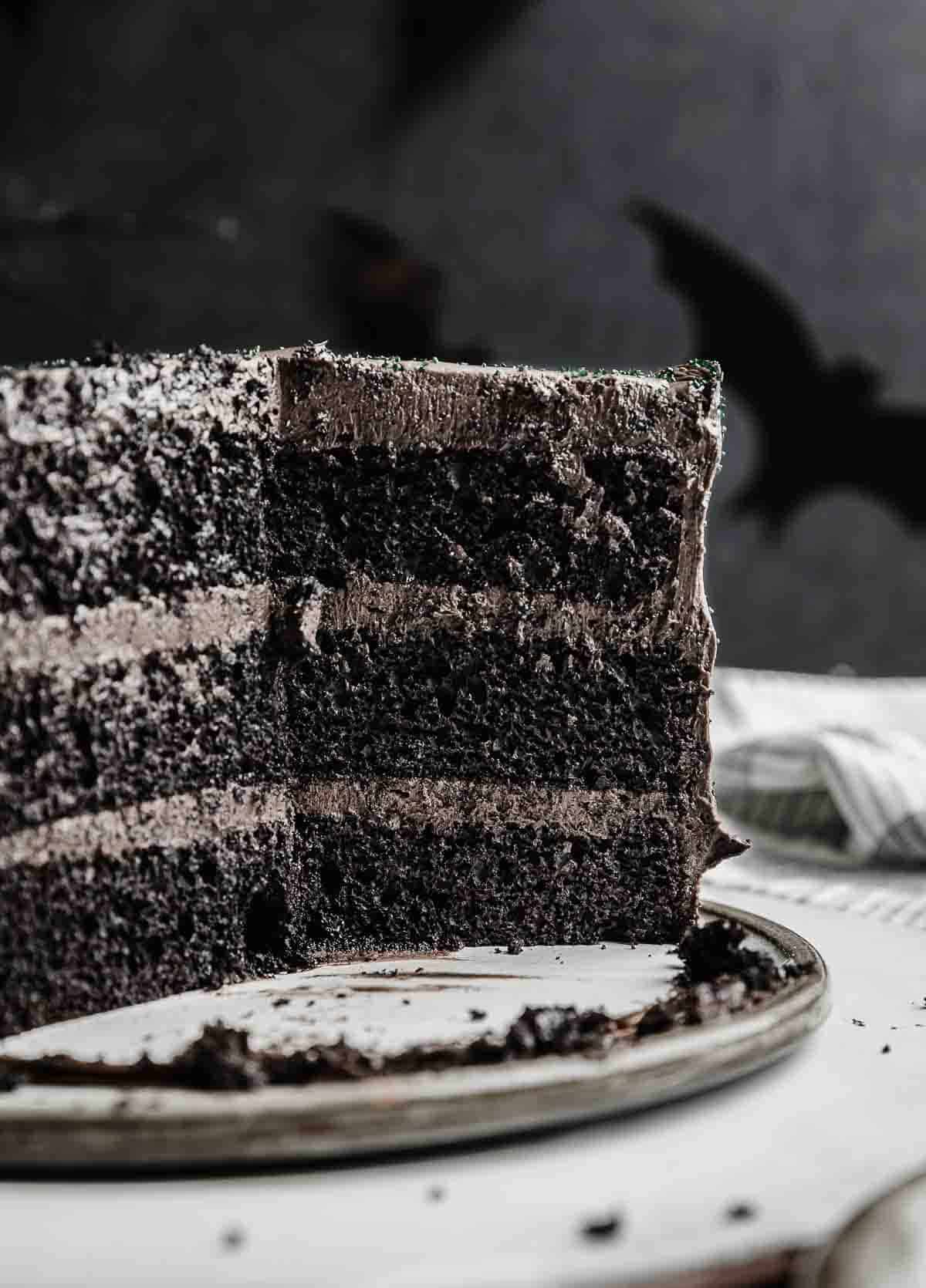 A Black Velvet Cake with several slices of cake removed to show the interior of the three tiered black layer cake.