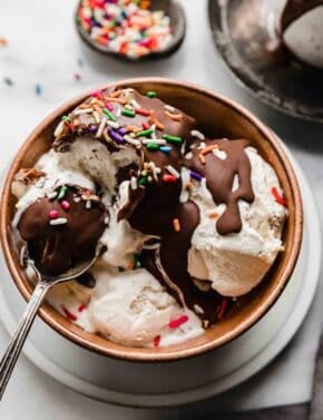 Magic Shell overtop vanilla ice cream, in a brown bowl, topped with sprinkles.