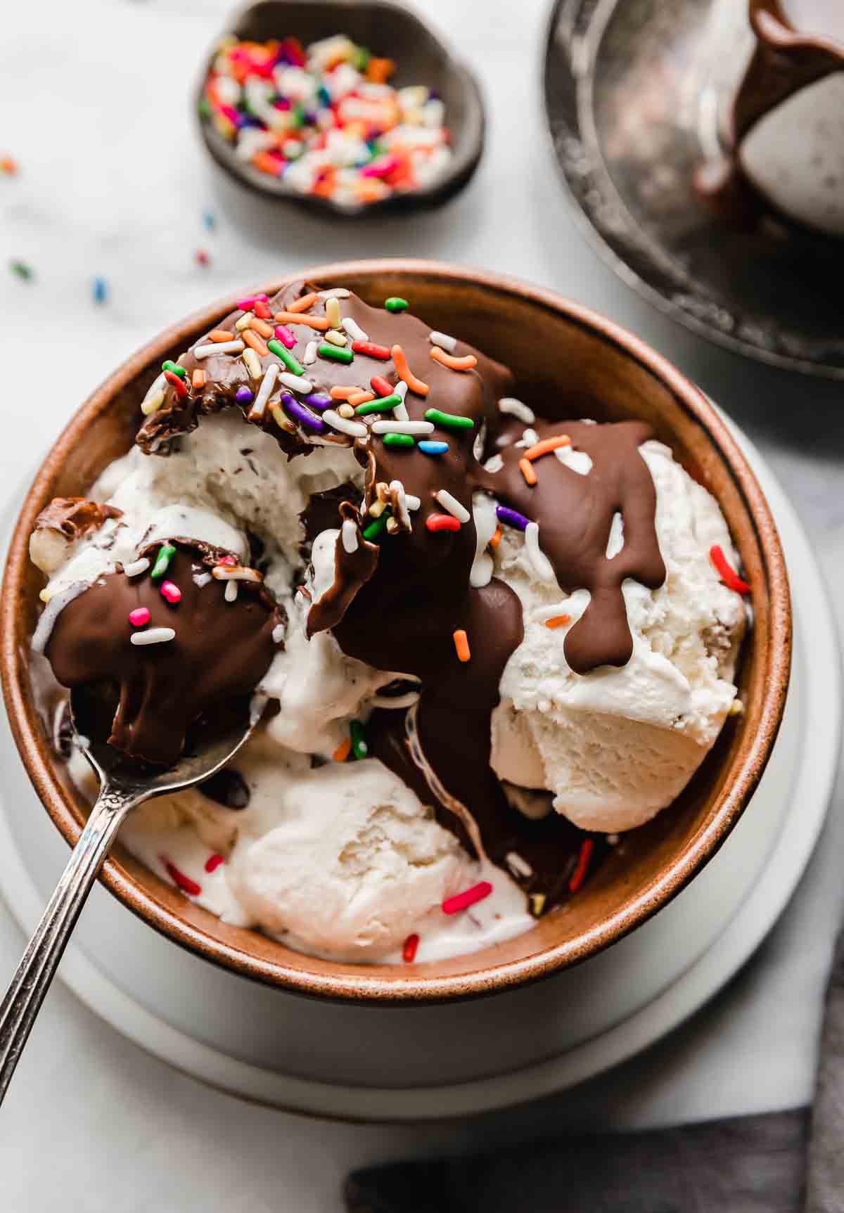 Magic Shell overtop vanilla ice cream, in a brown bowl, topped with sprinkles. 