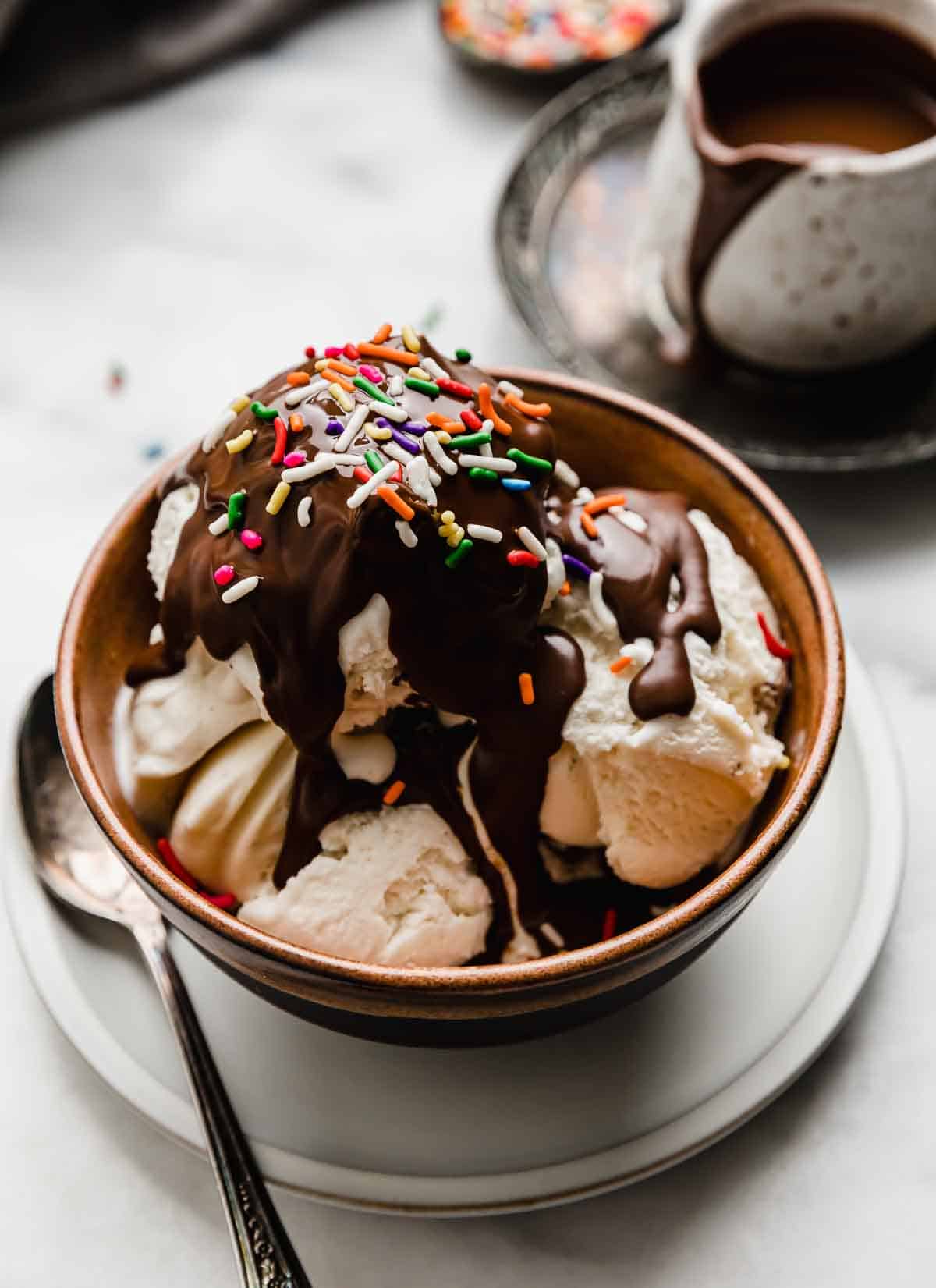 Vanilla ice cream in a brown bowl topped with homemade magic shell recipe and colorful sprinkles.