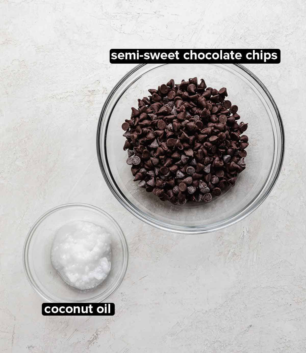 Magic Shell ingredients on a gray background: semi sweet chocolate chips and coconut oil.
