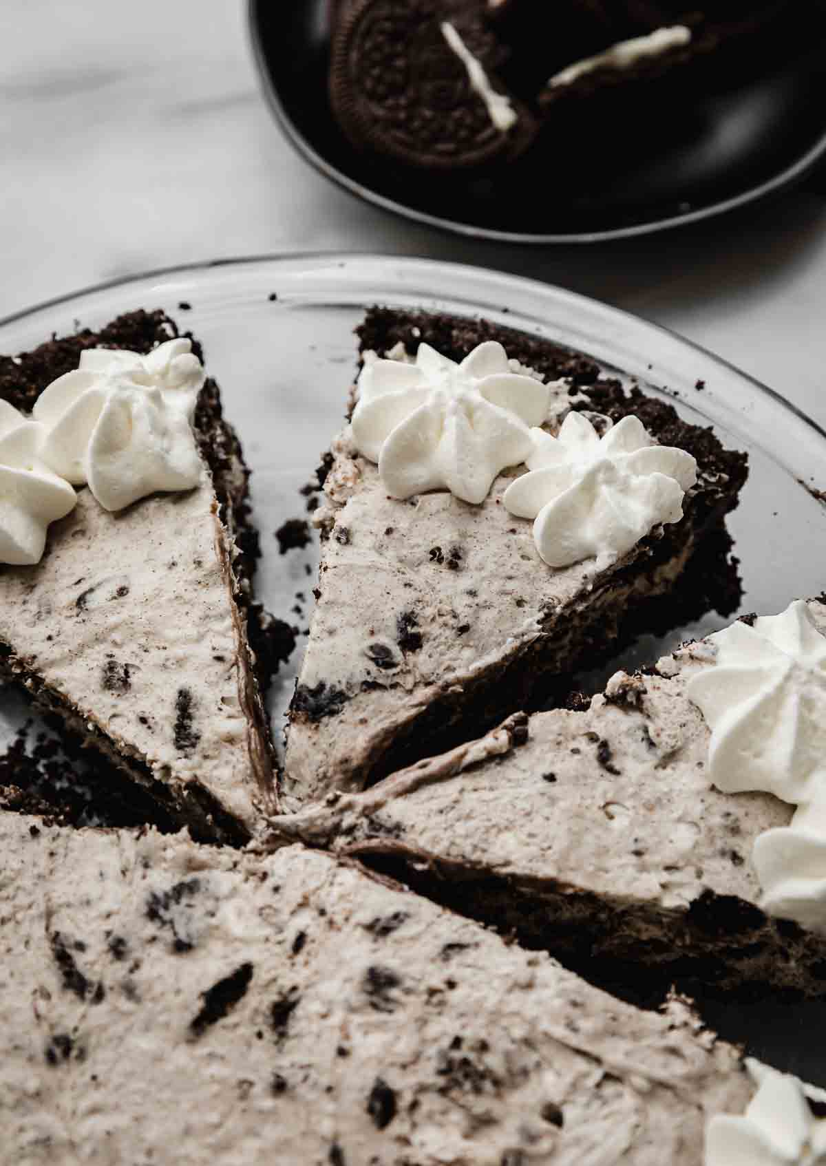 Cookies and Cream Pie cut into triangle slices and topped with whipped cream.