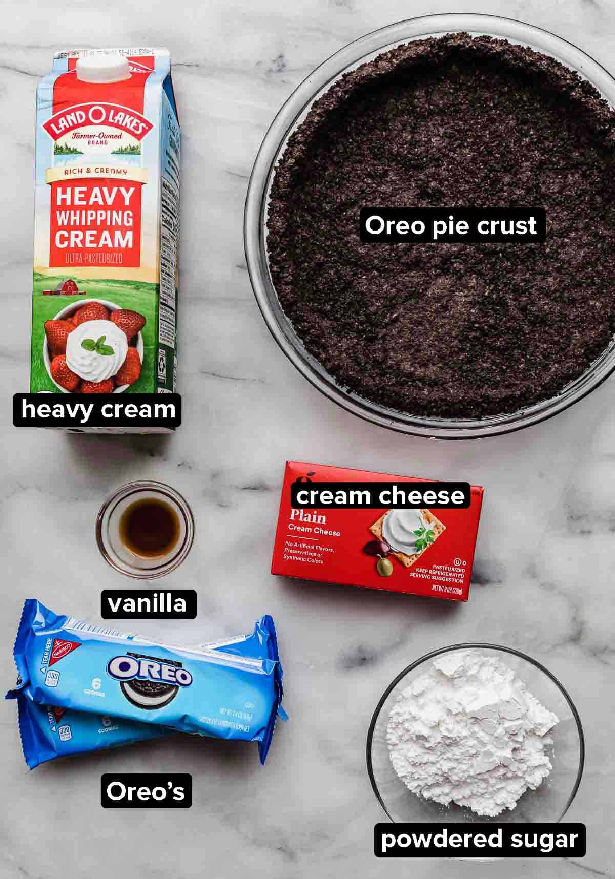 Cookies and Cream Pie (Oreo pie) ingredients on a white background: heavy cream, Oreo pie crust, Oreos, cream cheese, powdered sugar, vanilla.