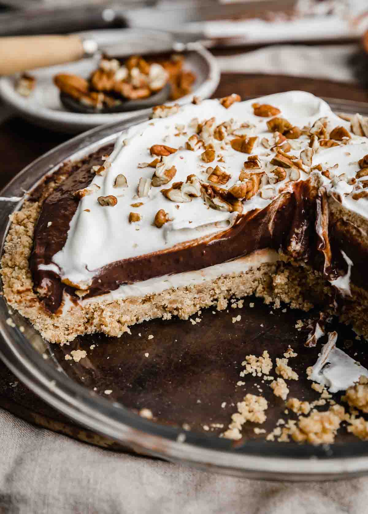 An Arkansas Possum Pie sliced into, showing the pecan shortbread crust topped with cream cheese filling, chocolate pudding then a whipped topping.