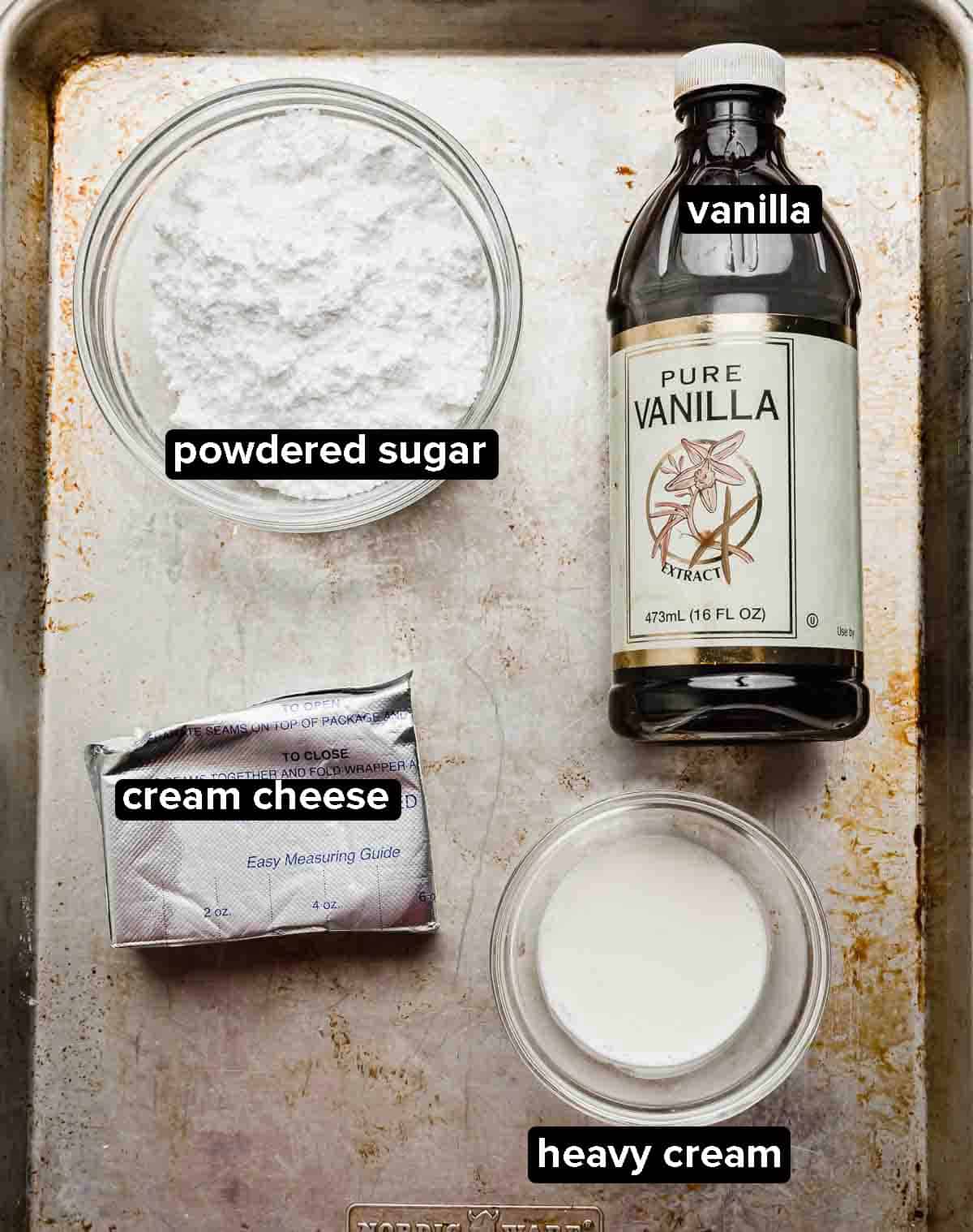 Ingredients used to make a cream cheese filling for the base of an Arkansas possum pie recipe, powdered sugar, cream cheese, heavy cream, and vanilla extract pictured on a baking sheet.