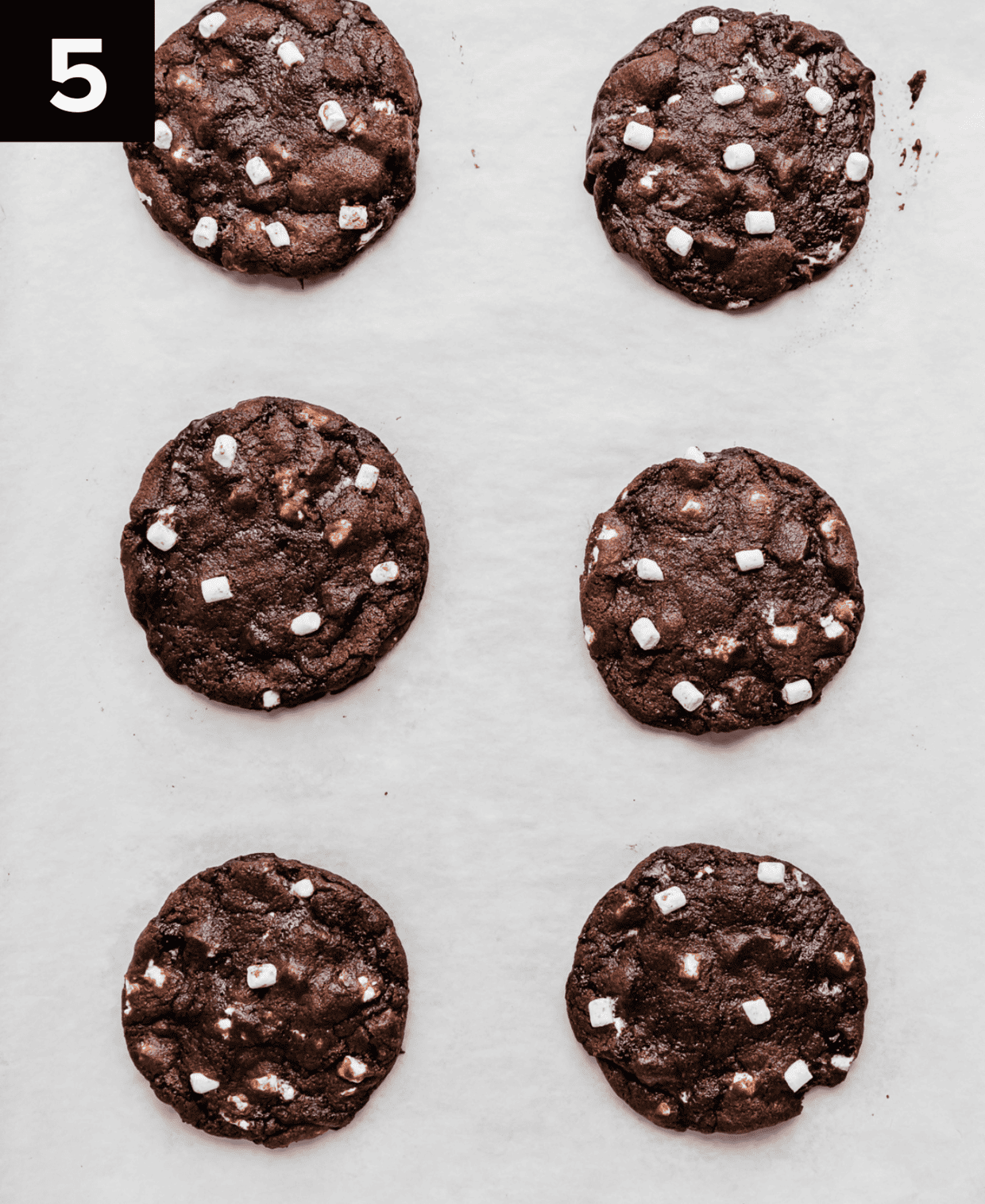 Baked hot chocolate cookies on a white parchment paper covered baking sheet.