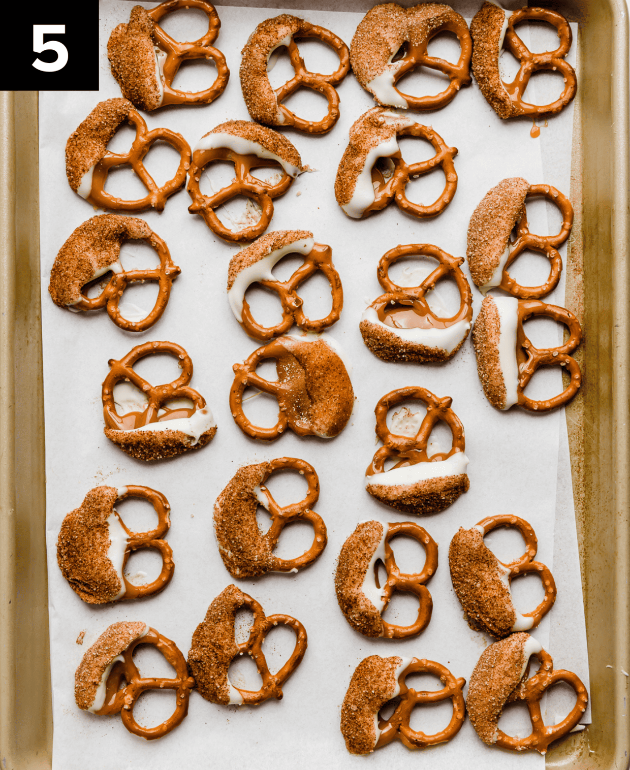 Caramel coated snickerdoodle pretzels on a white parchment paper.