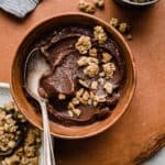Chocolate Acai smoothie in a brown bowl topped with granola.