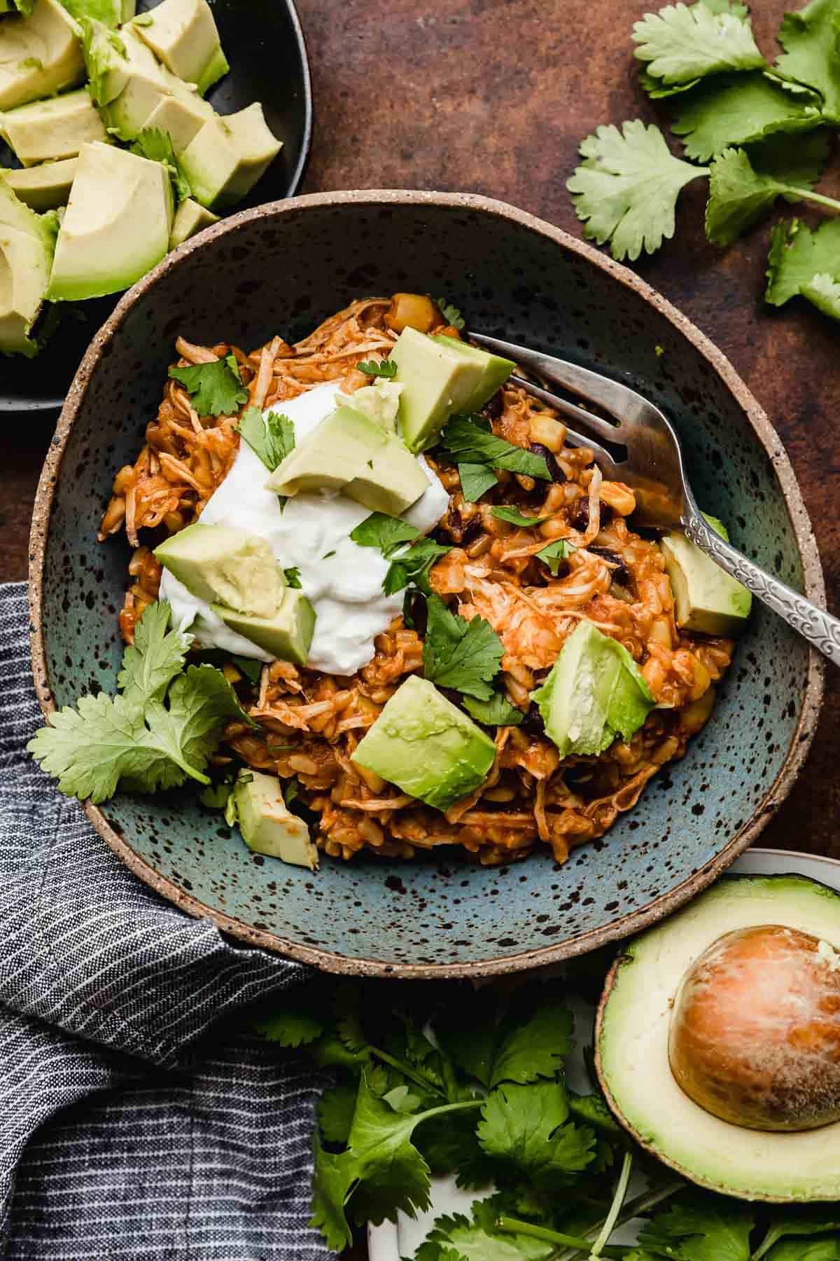 Instant Pot Chicken Taco Bowls in a blue bowl topped with sour cream, cilantro, and avocado.