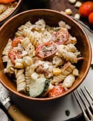 Chicken Bacon Ranch Pasta Salad in a brown bowl on a white plate.