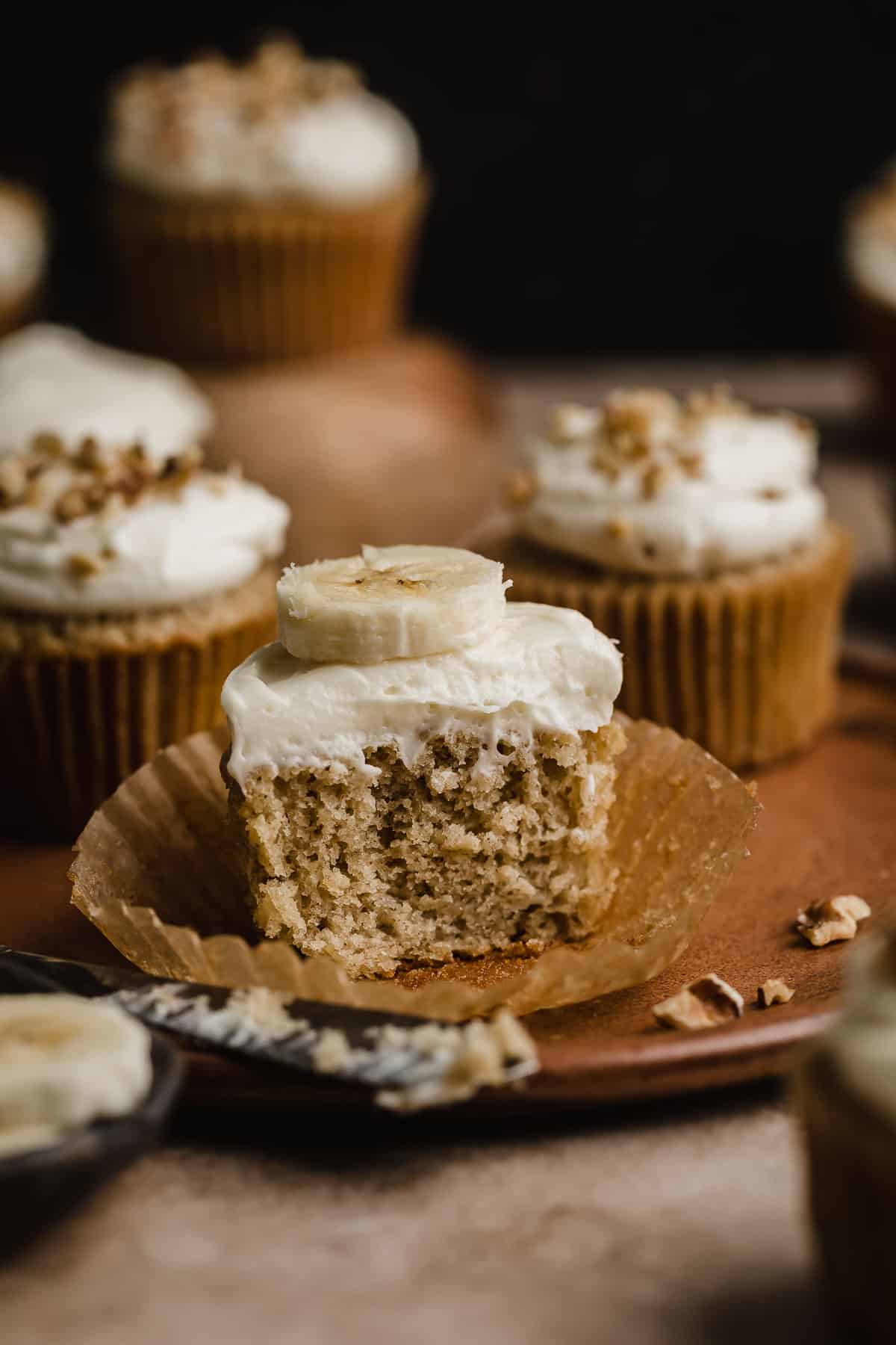 A Banana Cupcake sliced in half, showing how moist the banana cupcake is, and topped with a cream cheese frosting.