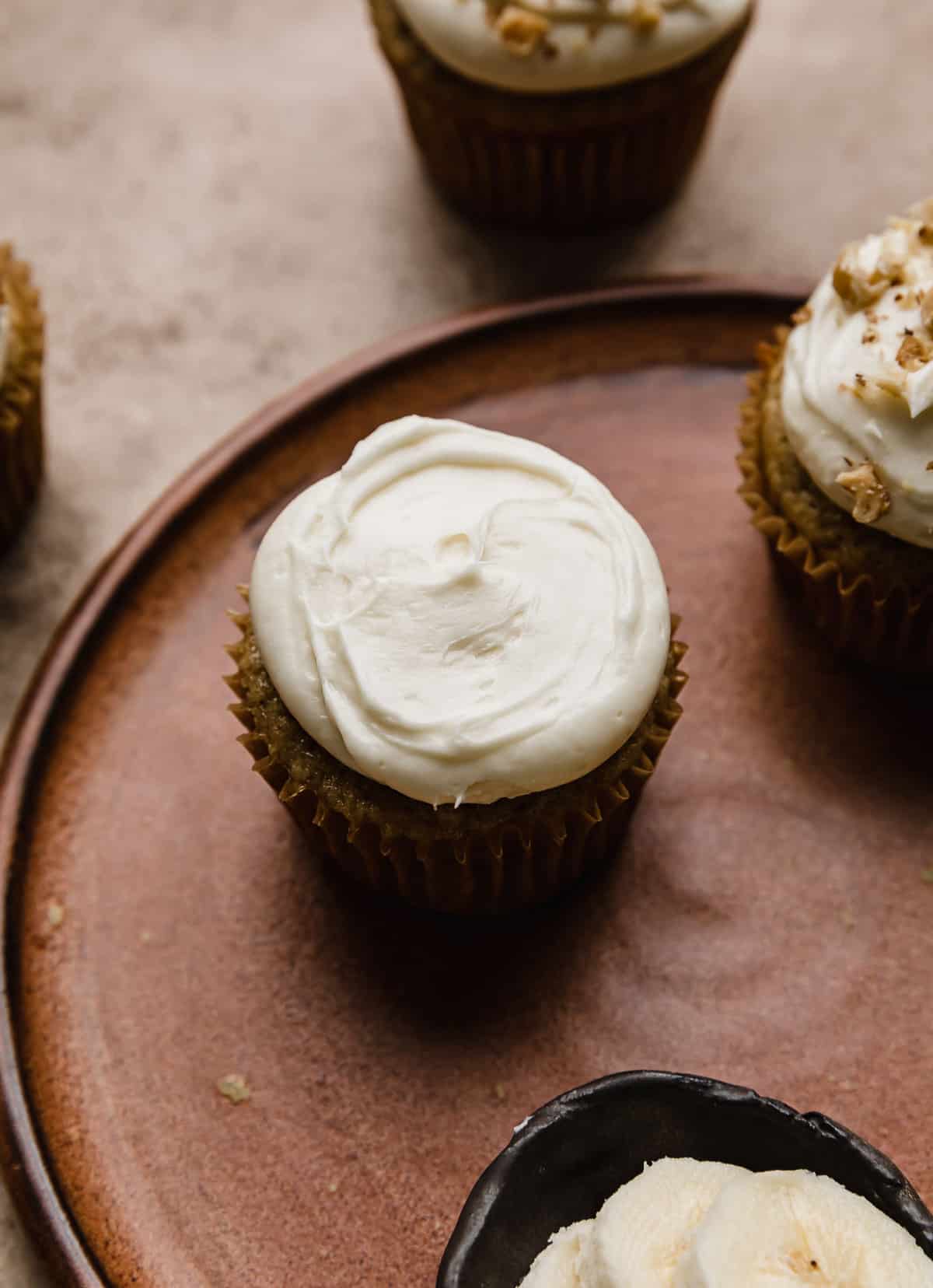 A banana cupcake topped with cream cheese frosting.