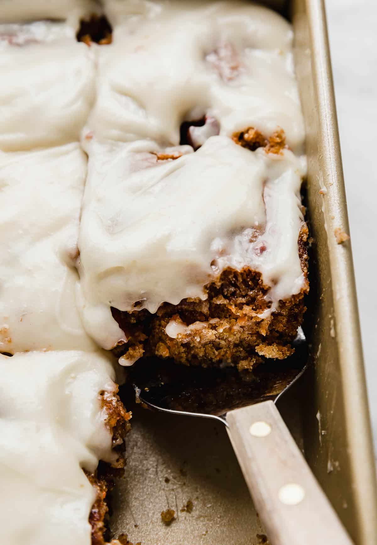 The best Carrot Coffee Cake cut into squares with a metal spatula scooping up one of the slices.