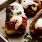 The best Italian Meatball Subs topped with melted cheese, on a baking sheet.