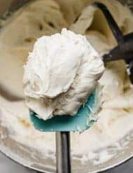 Small Batch Cream Cheese Frosting recipe on a turquoise rubber spatula over a bowl of cream cheese frosting.