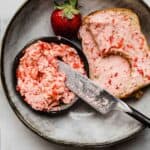 Fresh Strawberry Butter in a small black bowl, with chunky strawberry butter spread over two slices of toasted bread.