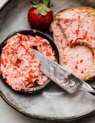 Fresh Strawberry Butter in a small black bowl, with chunky strawberry butter spread over two slices of toasted bread.