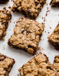 The best oatmeal cookie bars with chocolate chips, cut into squares on a white background with crumbs surrounding each brown butter oatmeal bar.