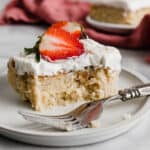 A slice of Mexican Tres Leches Cake on a white plate with a fork next to the cake.