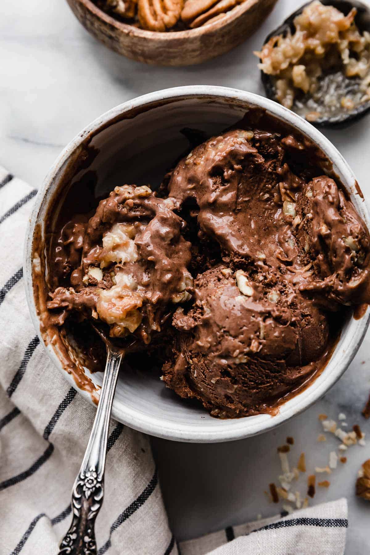 The best German Chocolate Cake Ice Cream in a white bowl with a spoon scooping out some of the coconut pecan chocolate ice cream.