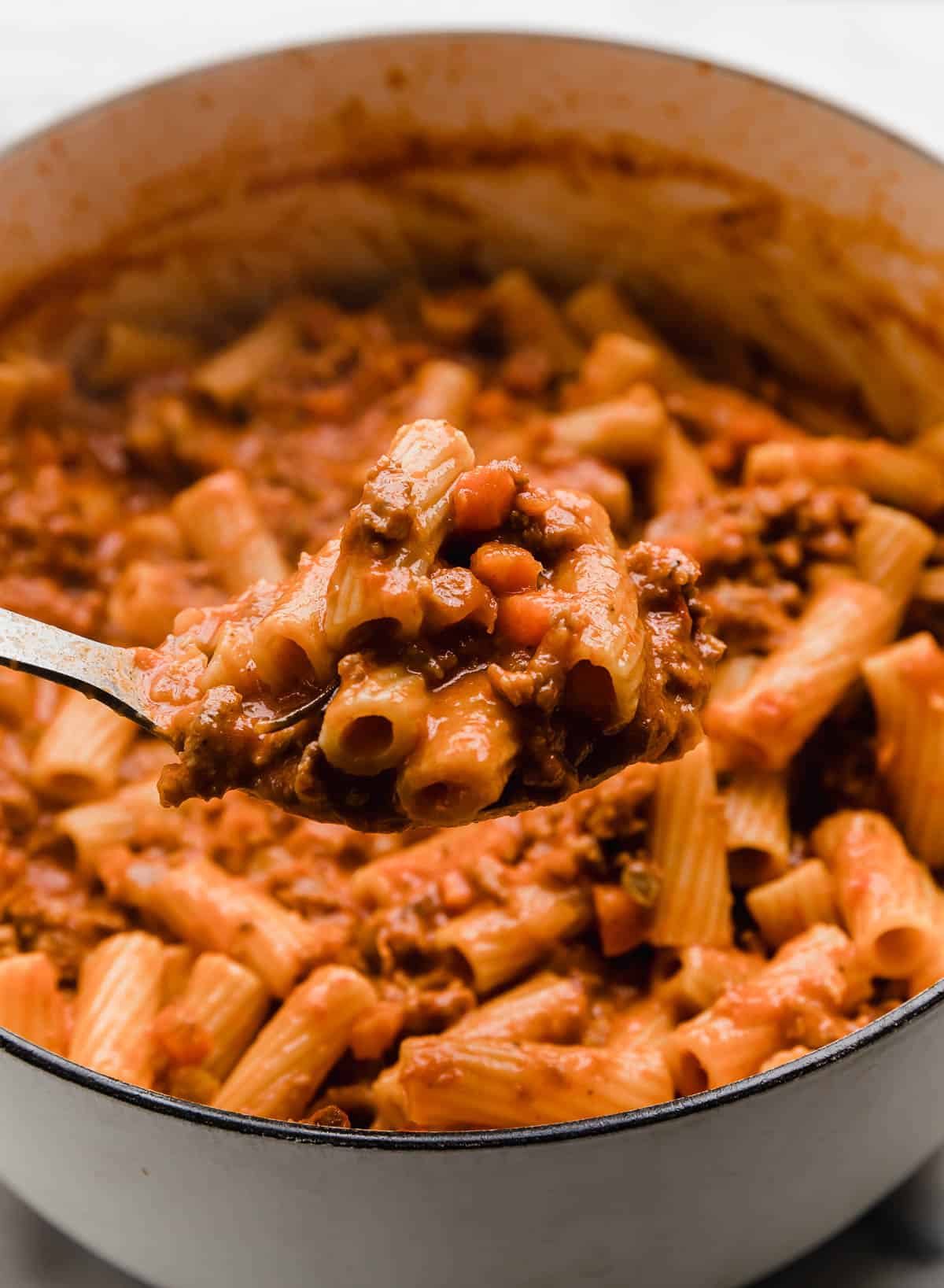 A serving spoon scooping up easy sausage ragu recipe from a pot.