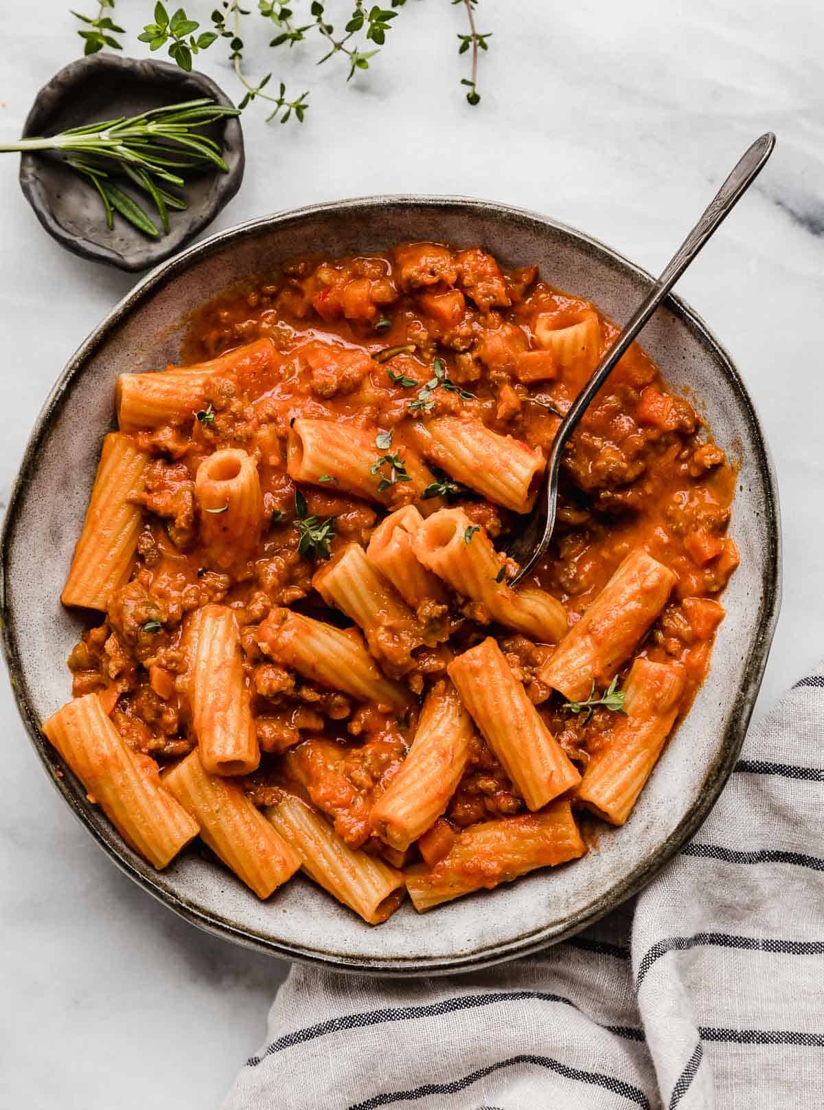 The best Sausage Ragu recipe in a gray pasta bowl with a fork piercing some of the rigatoni noodles.